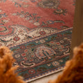 Handmade red Persian-style wool and cotton area rug featuring intricate floral patterns and a traditional bohemian border.