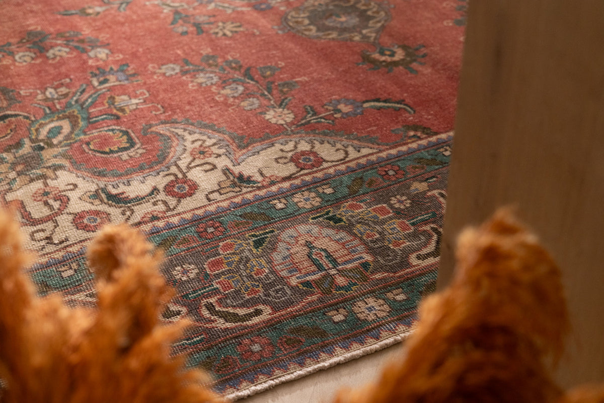 Handmade red Persian-style wool and cotton area rug featuring intricate floral patterns and a traditional bohemian border.