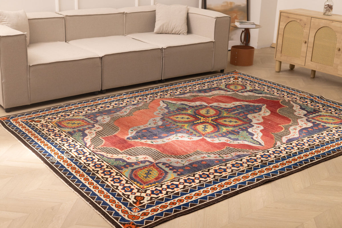 Oversized 7x10 Persian-style wool and cotton area rug featuring a red and navy floral maximalist pattern in a living room.