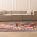 Oversized Persian-style wool and cotton rug with red and navy floral patterns in a modern living room.