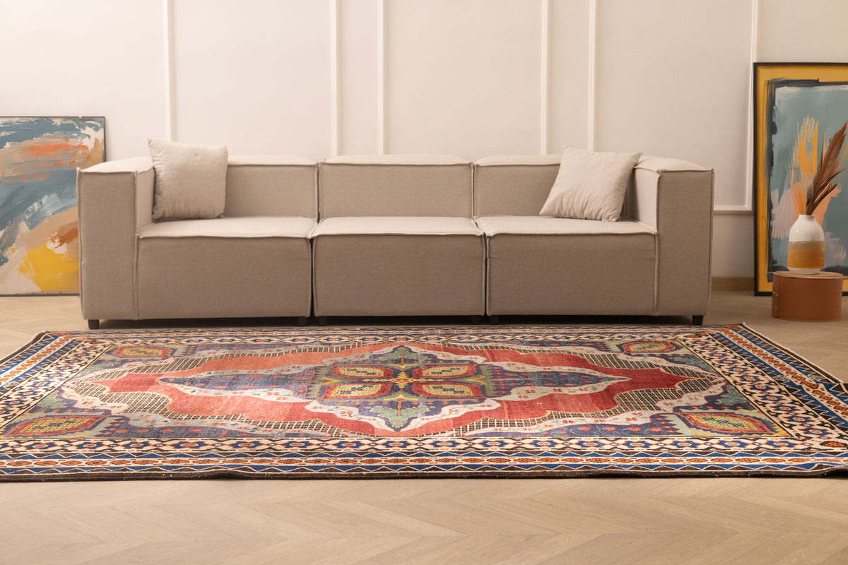 Oversized Persian-style wool and cotton rug with red and navy floral patterns in a modern living room.