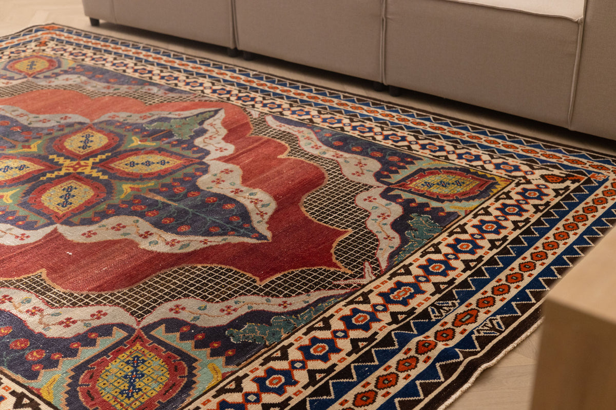 Handmade 7x10 ft Persian-style wool and cotton rug with red and navy floral patterns in a traditional bohemian design.