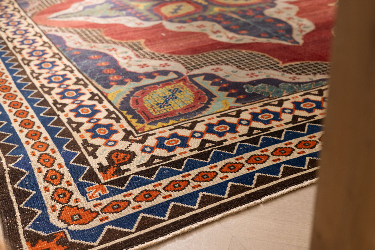Oversized wool and cotton Persian rug with red and navy floral patterns and a traditional bohemian border.