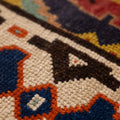 Close-up of a handmade wool and cotton Persian-style rug featuring intricate floral motifs in red, navy, and cream.