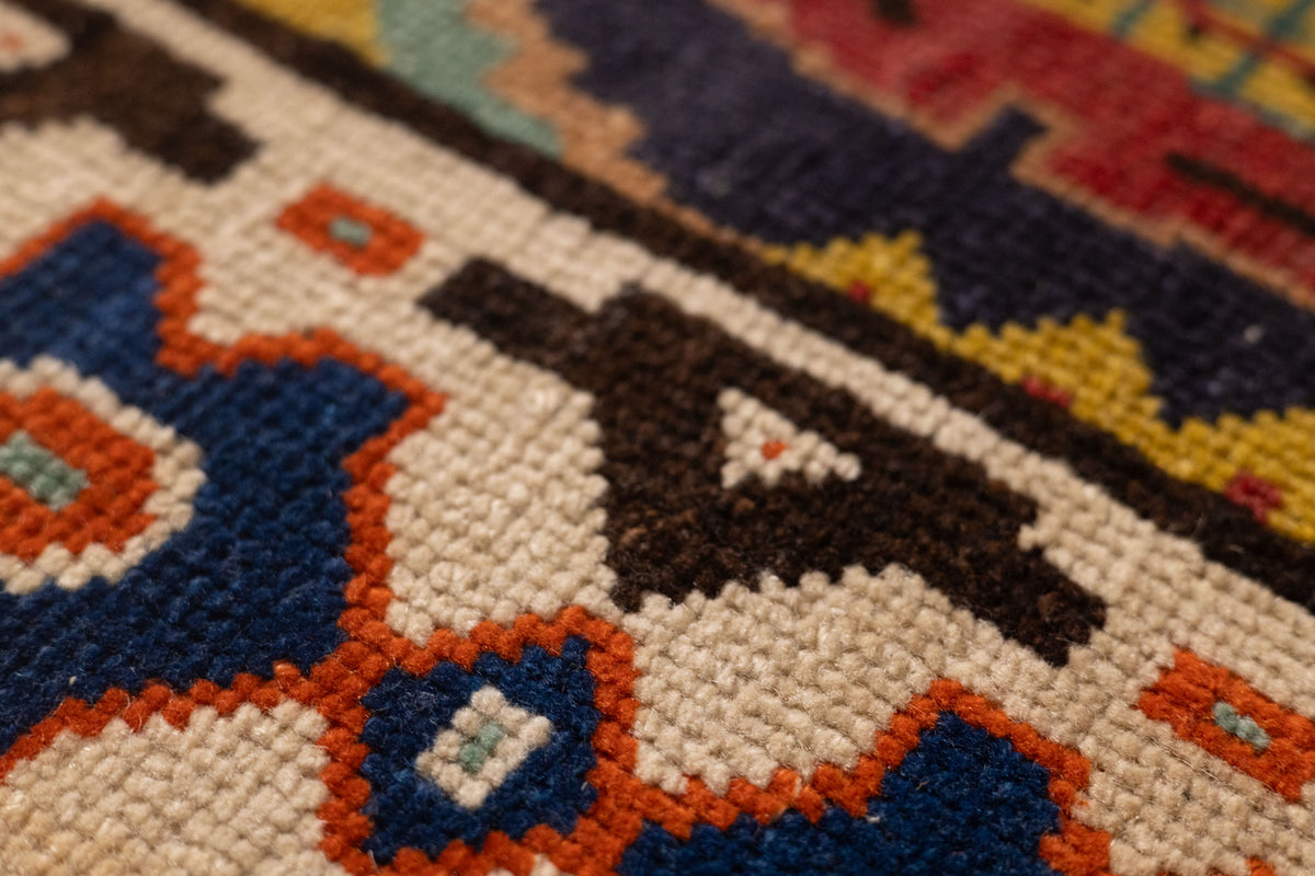 Close-up of a handmade wool and cotton Persian-style rug featuring intricate floral motifs in red, navy, and cream.