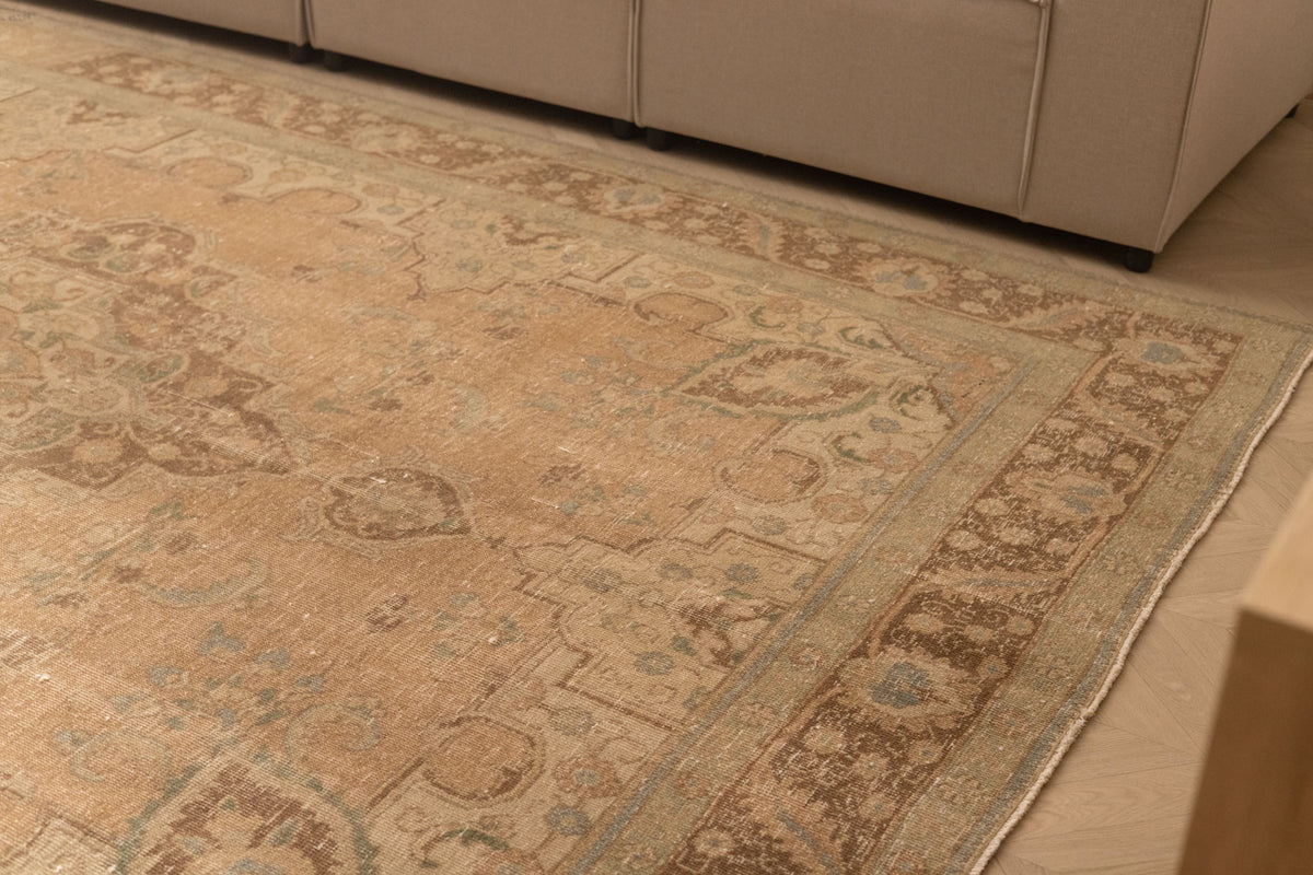 Oversized beige and brown Persian-style wool and cotton rug with traditional floral patterns.