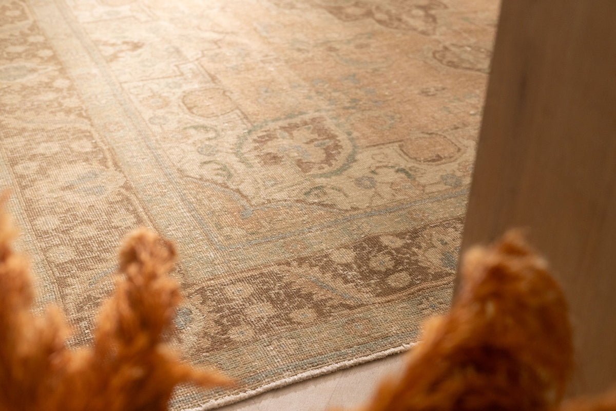 Oversized Persian-style wool and cotton area rug in beige and brown with traditional floral motifs.