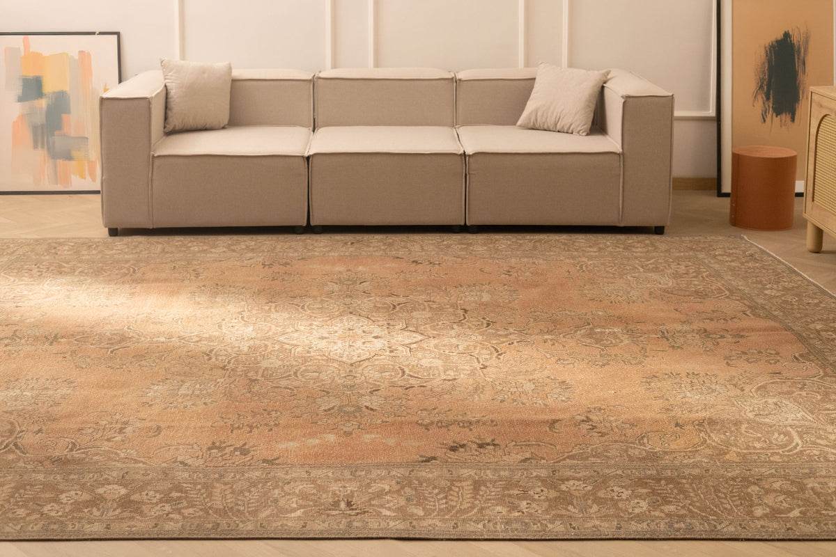 Oversized orange and brown Persian-style wool and cotton area rug with traditional floral patterns in a living room.