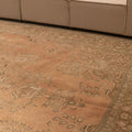 Oversized Persian-style wool and cotton area rug in orange and brown with traditional floral patterns.