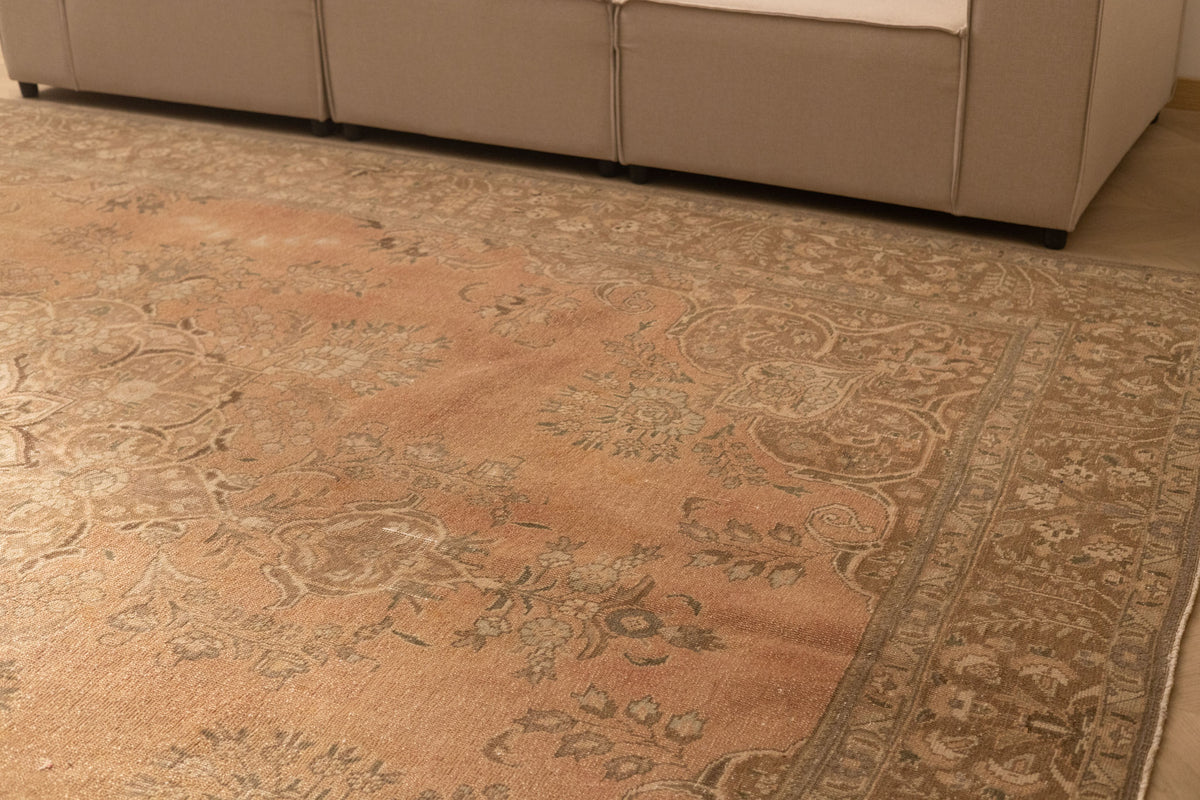Oversized Persian-style wool and cotton area rug in orange and brown with traditional floral patterns.