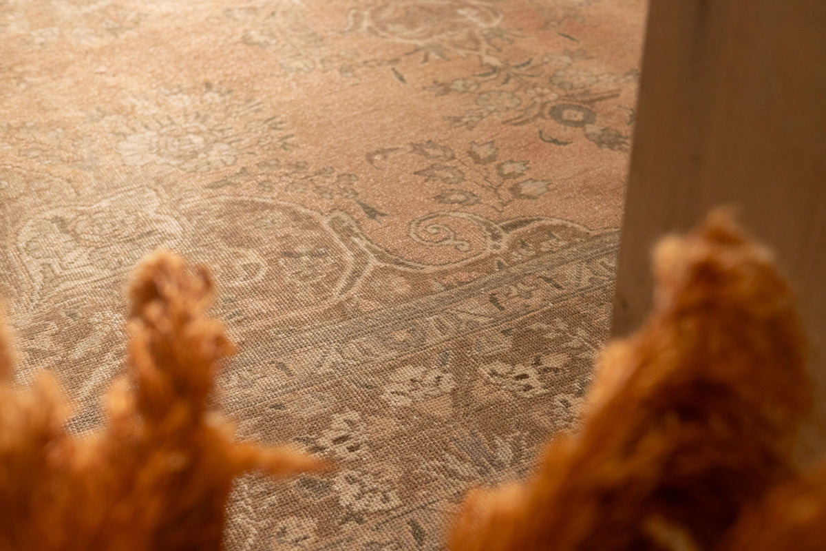Oversized Persian-style wool and cotton area rug in orange and brown with traditional floral patterns.