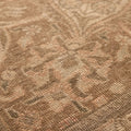 Close-up of a handmade wool and cotton Persian area rug featuring intricate orange and brown floral patterns.