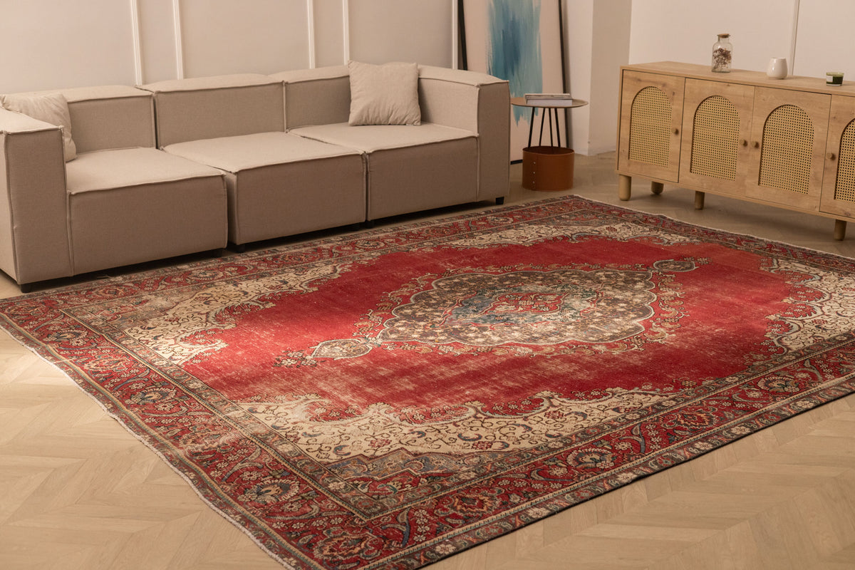Oversized red Persian-style area rug with intricate floral patterns, crafted from a wool and cotton blend in a living room.