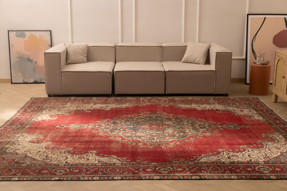 Oversized red Persian-style wool and cotton area rug featuring traditional floral motifs in a living room setting.