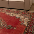 Oversized red Persian-style wool and cotton area rug featuring intricate floral motifs and traditional bohemian patterns.