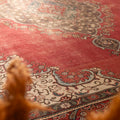 Oversized red Persian-style area rug with intricate floral patterns, handmade from wool and cotton in a traditional bohemian design.