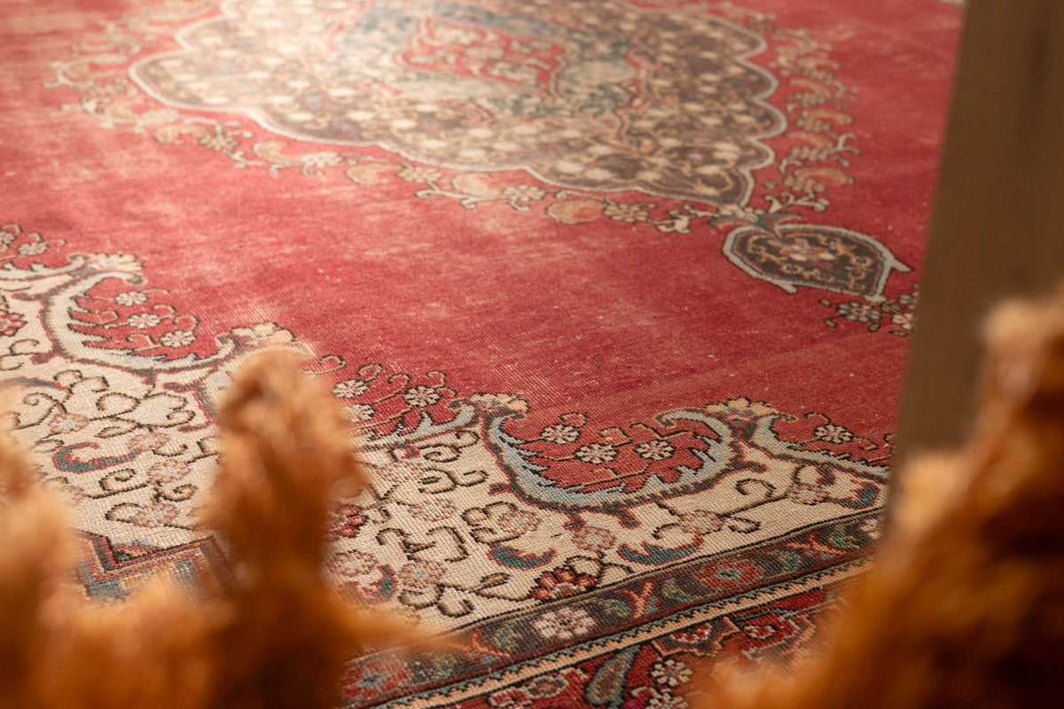Oversized red Persian-style area rug with intricate floral patterns, handmade from wool and cotton in a traditional bohemian design.