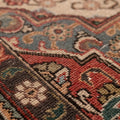 Close-up of a handmade wool and cotton Persian-style rug featuring intricate red and blue floral patterns.