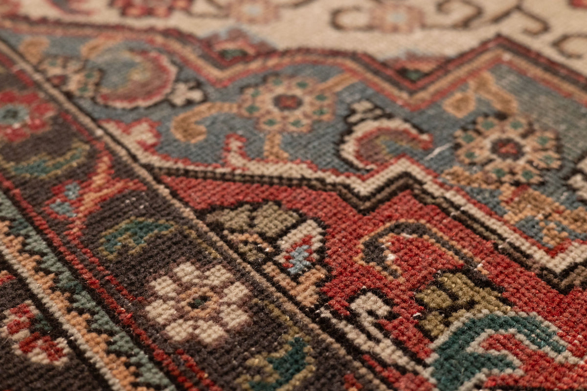Close-up of a handmade wool and cotton Persian-style rug featuring intricate red and blue floral patterns.