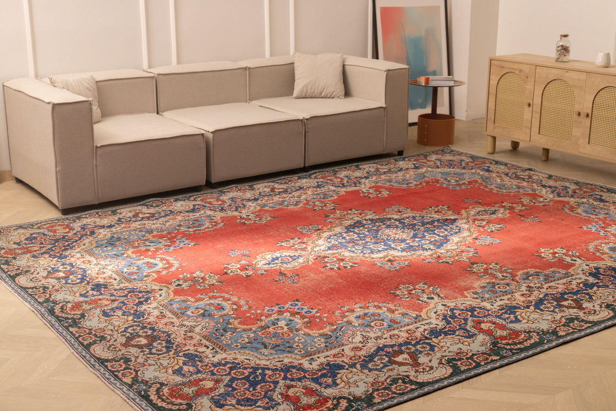 Oversized red and navy Persian-style wool and cotton area rug featuring intricate floral patterns in a living room.