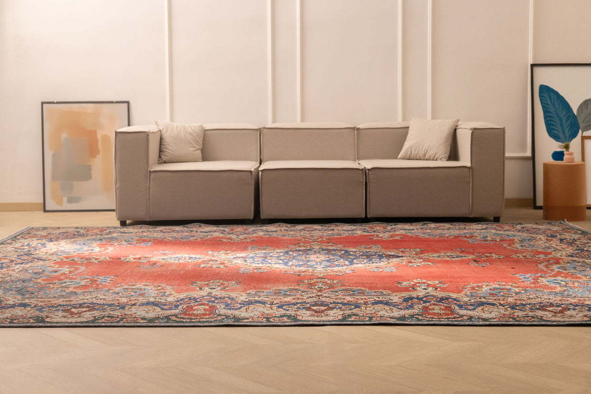Oversized red and navy Persian-style wool and cotton area rug with traditional floral patterns in a living room.