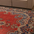 Oversized red and navy Persian-style wool and cotton area rug featuring intricate floral patterns and traditional motifs.