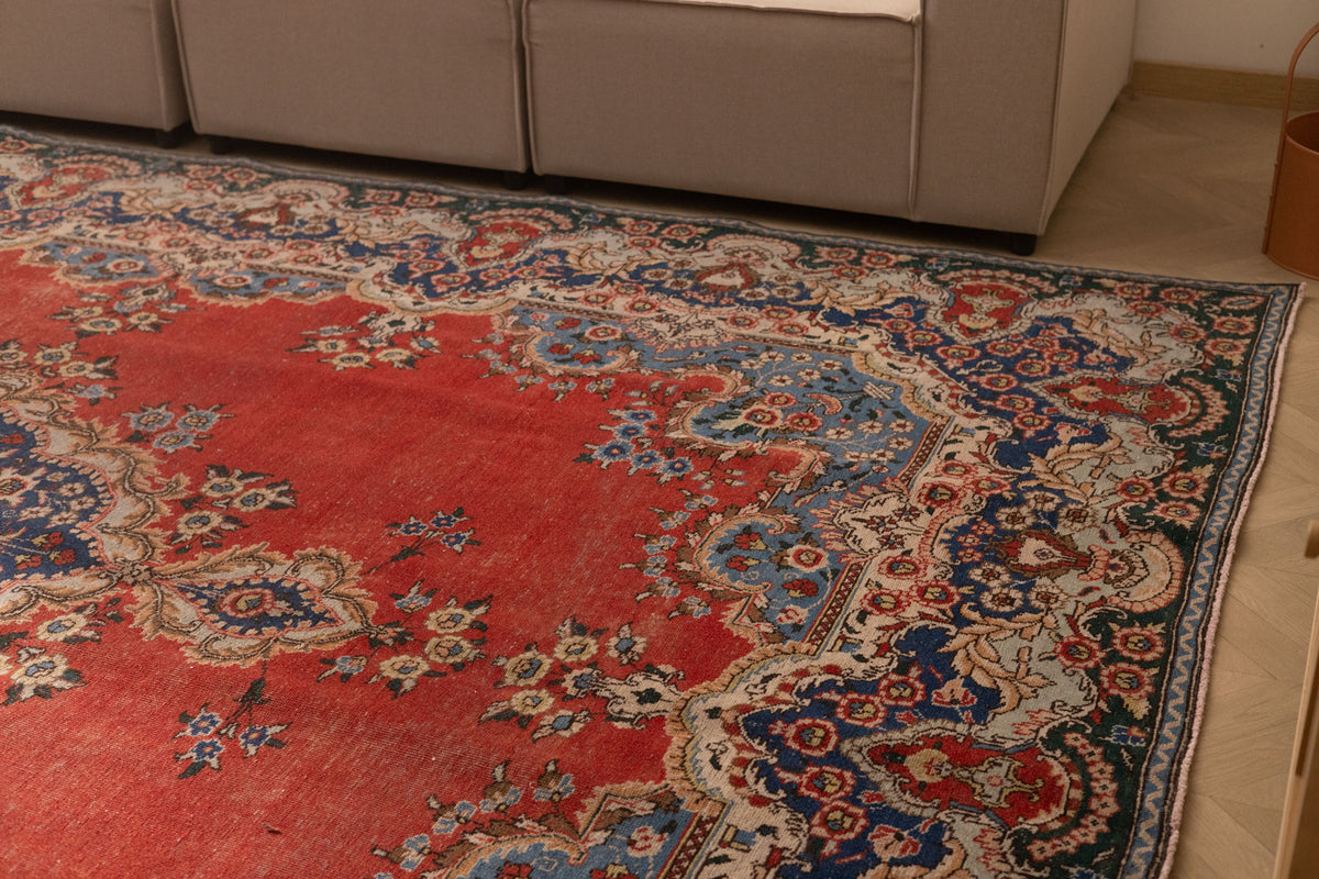 Oversized red and navy Persian-style wool and cotton area rug featuring intricate floral patterns and traditional motifs.