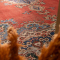 Oversized Persian-style area rug in red and navy with intricate floral patterns, handmade from wool and cotton.