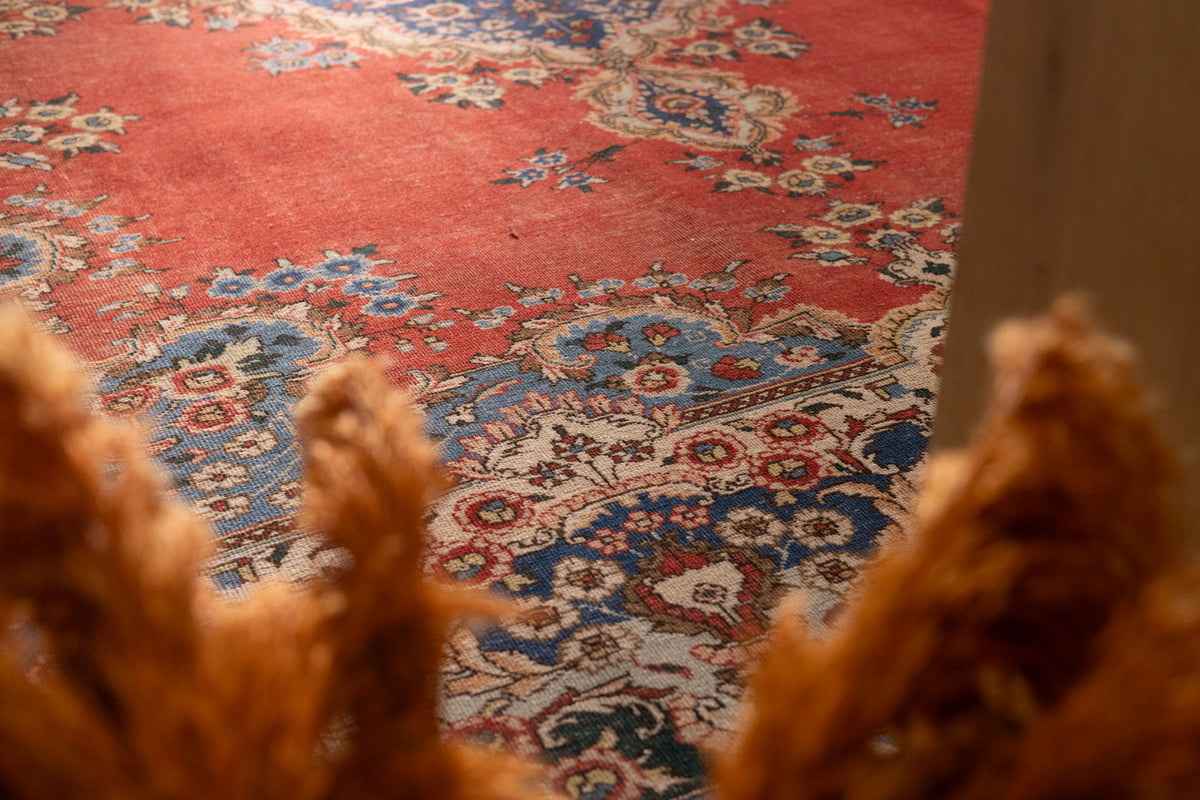 Oversized Persian-style area rug in red and navy with intricate floral patterns, handmade from wool and cotton.