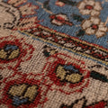 Close-up of a handmade wool and cotton Persian-style rug featuring intricate red and navy floral patterns.