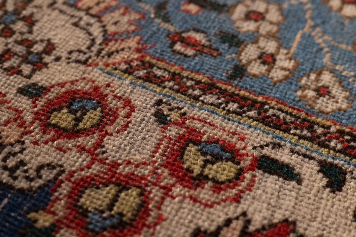 Close-up of a handmade wool and cotton Persian-style rug featuring intricate red and navy floral patterns.