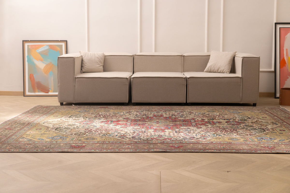 Oversized Persian-style wool and cotton rug featuring intricate red and floral patterns in a bohemian living room.