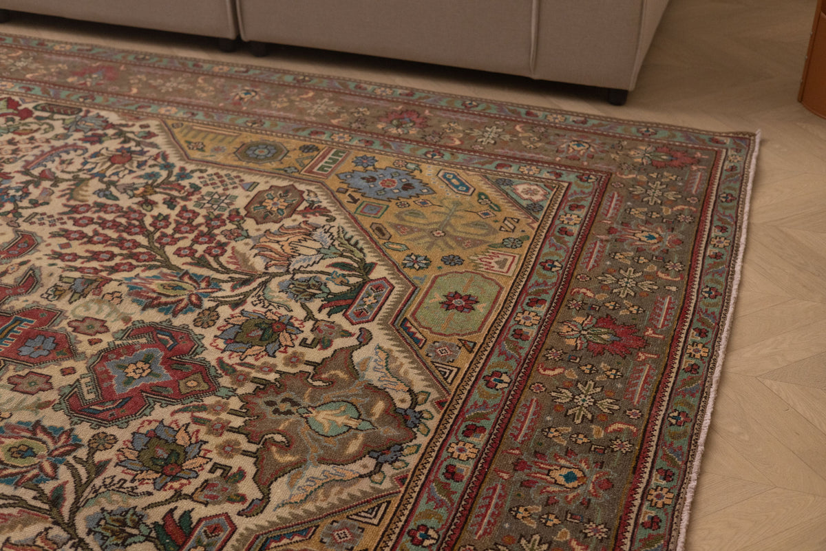 Oversized handmade wool and cotton Persian rug with intricate red, white, and floral bohemian patterns on a light wood floor.