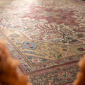 Oversized wool and cotton Persian-style area rug featuring intricate red and floral patterns in a traditional bohemian design.