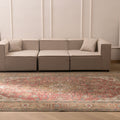 Oversized Persian-style wool and cotton area rug with red and brown floral patterns in a bohemian living room.