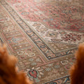 Oversized Persian-style wool and cotton rug in red and brown with intricate floral motifs and traditional patterns.