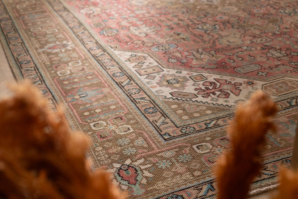 Oversized Persian-style wool and cotton rug in red and brown with intricate floral motifs and traditional patterns.