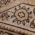Close-up of a handmade wool and cotton Persian-style rug featuring intricate brown and beige floral motifs.