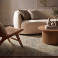 Muted green and purple distressed vintage Turkish rug in a modern minimal living room with a boucle sofa