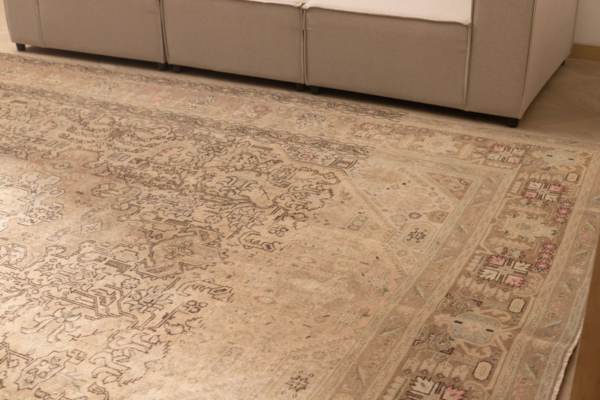 Oversized beige Persian-style wool and cotton rug with intricate geometric floral motifs in a traditional farmhouse design.