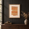 Framed vintage kilim fragment wall art in orange, khaki, sand hanging on a dark wall above a wooden console