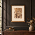 Framed vintage rug fragment wall art in brown, gold, ivory hanging on a dark wall above a wooden console