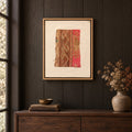 Framed vintage kilim fragment wall art in brown, tan, pink hanging on a dark wall above a wooden console