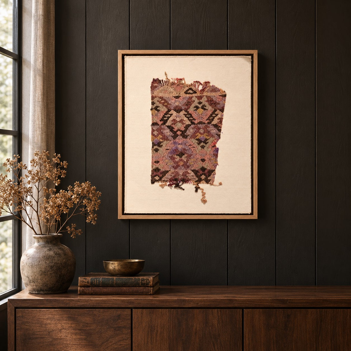 Framed vintage kilim fragment wall art in mauve, plum, ochre hanging on a dark wall above a wooden console