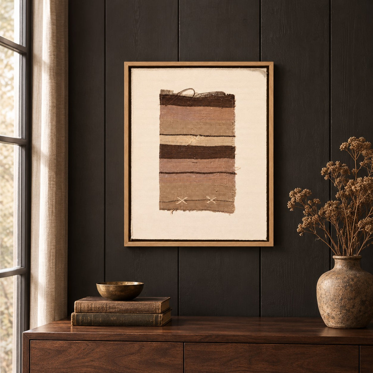 Framed vintage kilim fragment wall art in brown, taupe, ivory hanging on a dark wall above a wooden console
