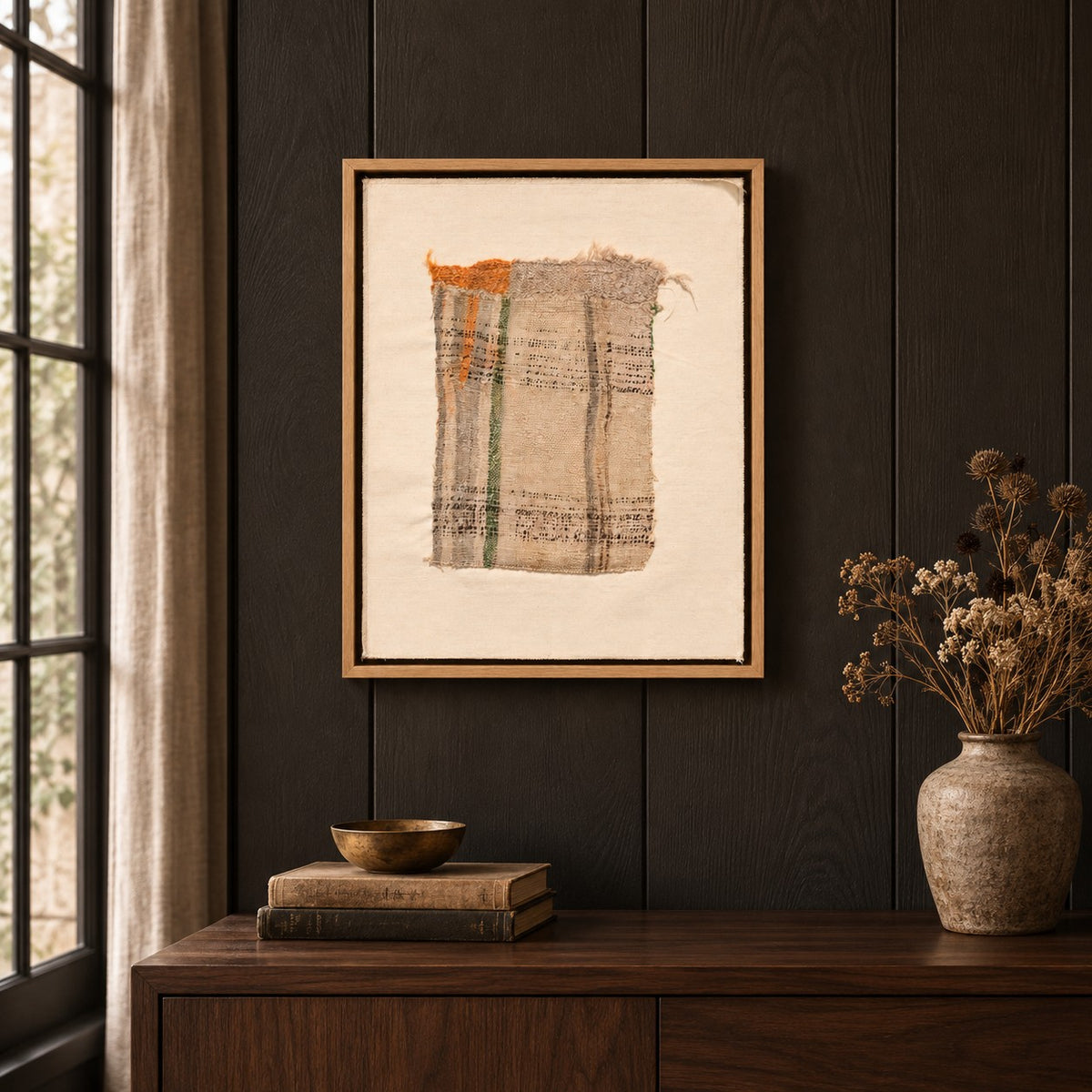 Framed vintage kilim fragment wall art in ivory, green, orange hanging on a dark wall above a wooden console