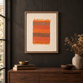Framed vintage kilim fragment wall art in orange, taupe, brown hanging on a dark wall above a wooden console