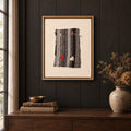 Framed vintage kilim fragment wall art in black, gray, ivory, red hanging on a dark wall above a wooden console