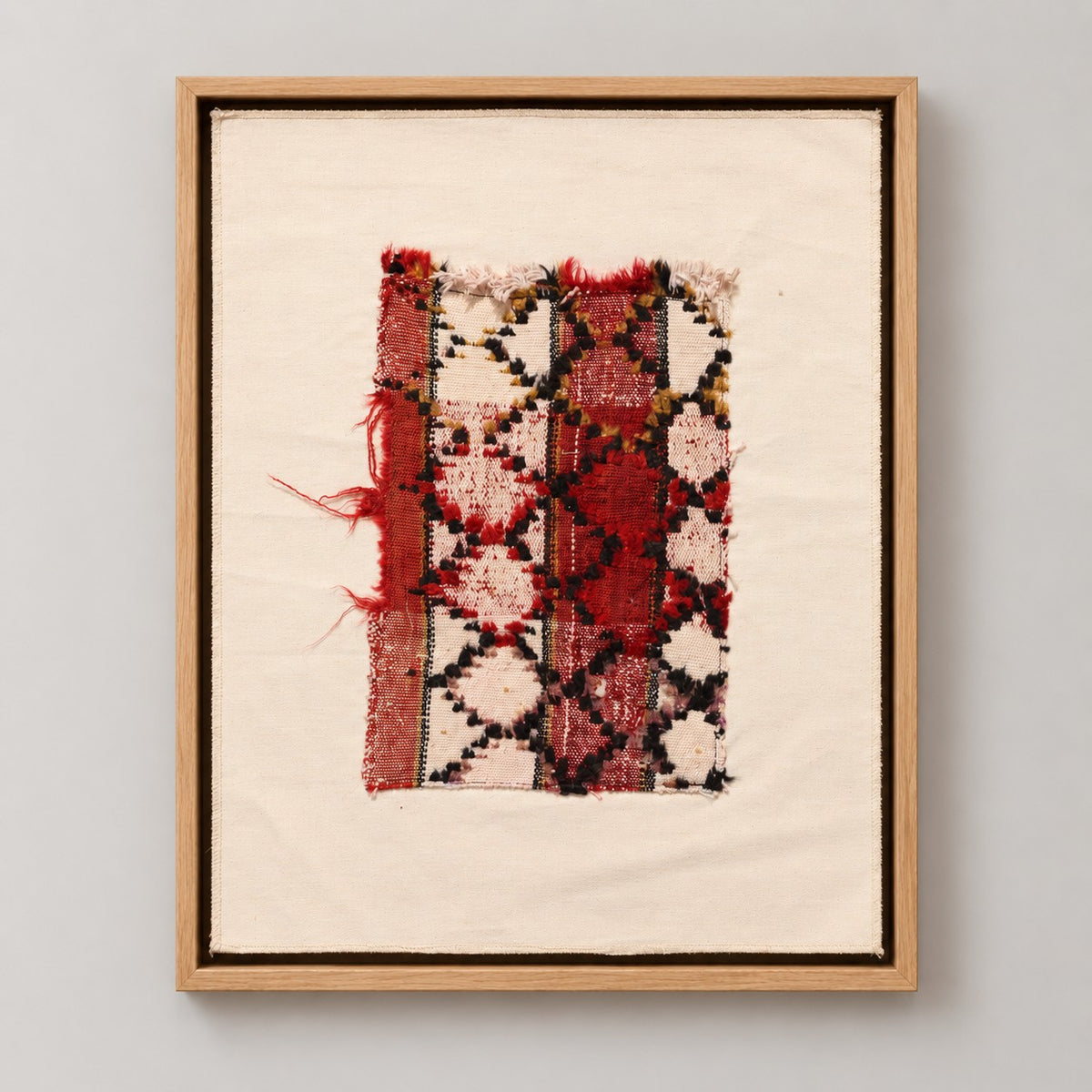 Framed vintage rug fragment wall art in red, ivory, black