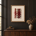 Framed vintage rug fragment wall art in red, ivory, black hanging on a dark wall above a wooden console